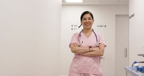 Nurse standing in radiology corridor wearing pink scrubs, stethoscope and smartwatch