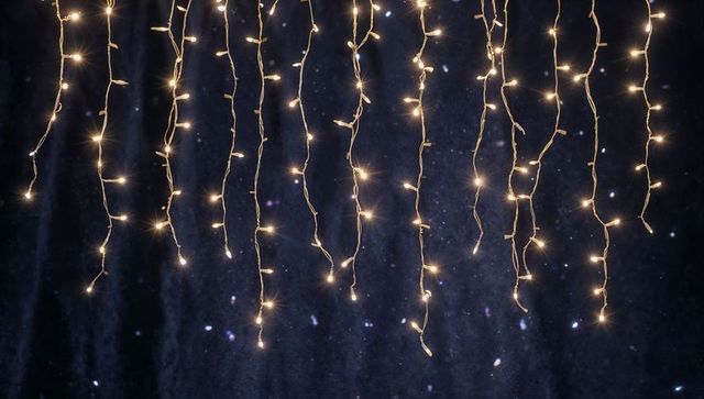 Warm White Fairy Light Curtains Hanging Over Dark Navy Backdrop Creating Festive Twinkle Bokeh