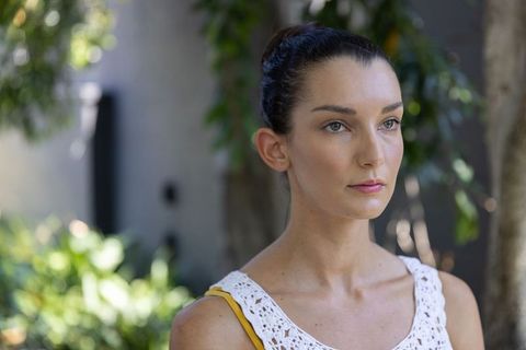 Mid adult woman gazing right in garden wearing white crochet top, natural light