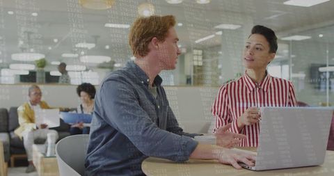 Professionals Collaborating in Modern Office Lounge with Laptops and Notebooks