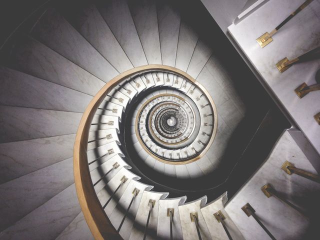 Elegant spiral stone staircase spiraling downwards, creating a mesmerizing and hypnotic visual pattern. Suitable for use in architectural presentations, interior design inspirations, and art projects focusing on symmetry and geometric shapes.