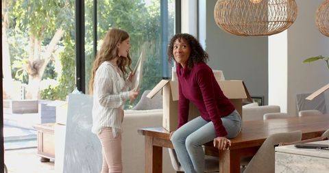 Female Friends Unpacking and Sharing Joyful Moments in Bright Living Room