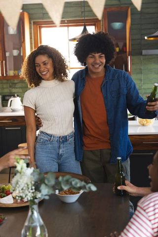 Couple smiling and embracing while enjoying drinks during cozy home kitchen gathering