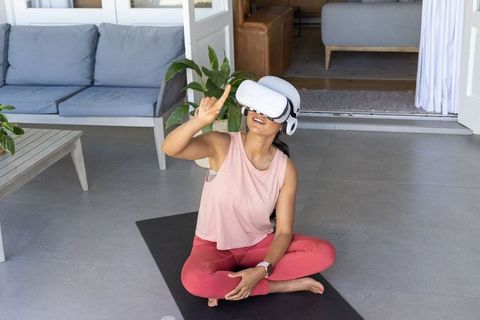 African american woman practicing yoga with vr headset on patio for home fitness and mindfulness