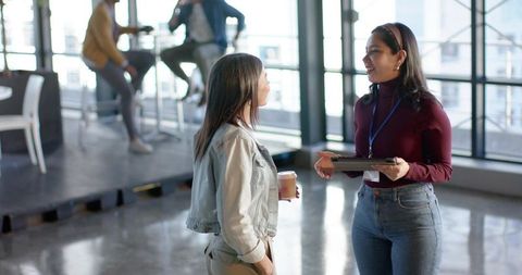 Diverse female coworkers talking and networking in modern open-plan coworking space