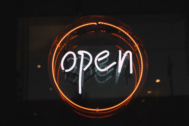 Neon open sign glowing against dark background, perfect for illustrating themes related to open businesses, late-night operations, welcoming guests, and promoting store front visibility. Ideal for use in marketing materials, business promotions, hospitality, and bar or restaurant advertisements.