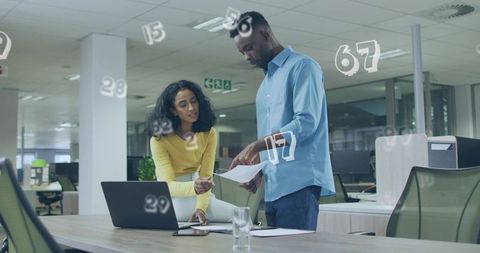 Collaborating professionals reviewing papers with AR data overlays in open-plan office