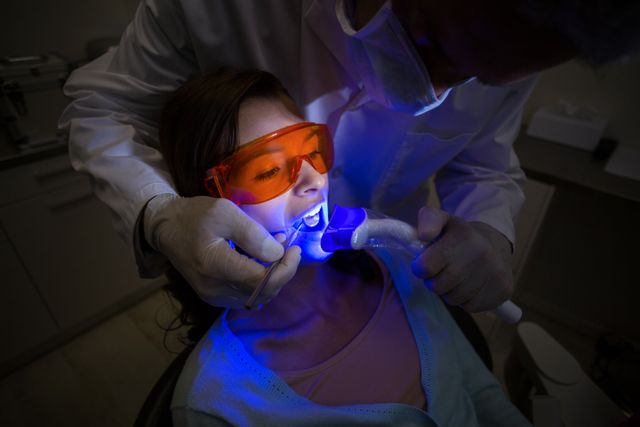 Dentist examining a female patient with dental tool at dental clinic