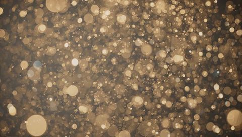 Glowing golden bokeh orbs creating depth with glitter particles and warm haze