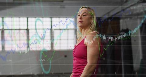 Confident Athletic Woman Standing in Industrial Gym with Financial Chart Overlay, Focused