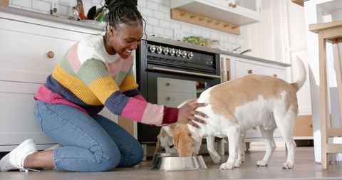 Happy woman feeding dog in cozy kitchen setting