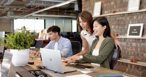 Diverse Coworkers Collaborating in Modern Open-Plan Office with Laptops