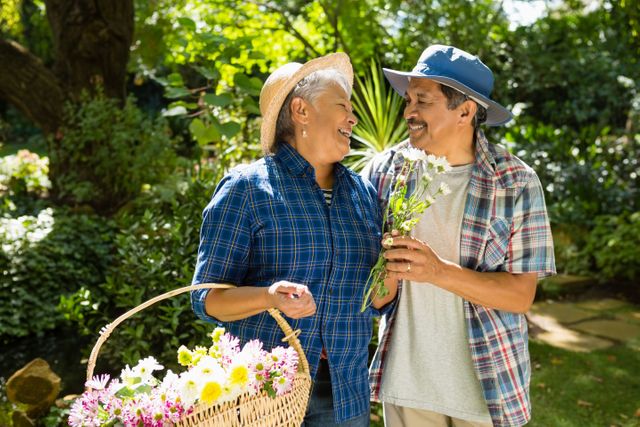 Senior couple walking in garden with flower basket in the park