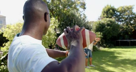 Active friends enjoying outdoor game of catch with football