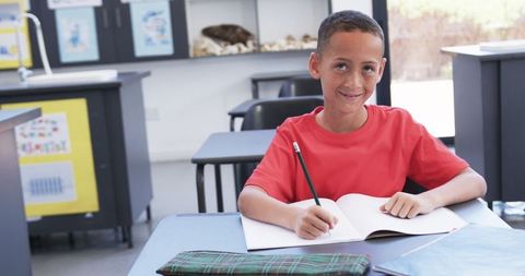 Young Student Writing Passionately in Classroom