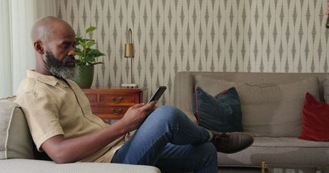Man Relaxing in Living Room Using Smartphone Comfortably