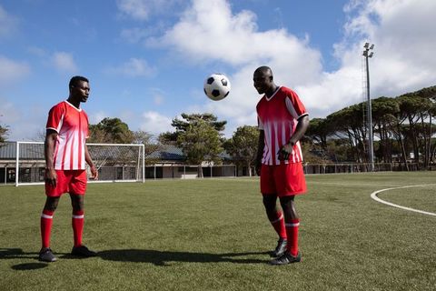 Afro american teammates heading soccer ball on field