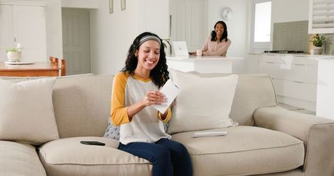 Women enjoying leisure time reading letter in cozy home