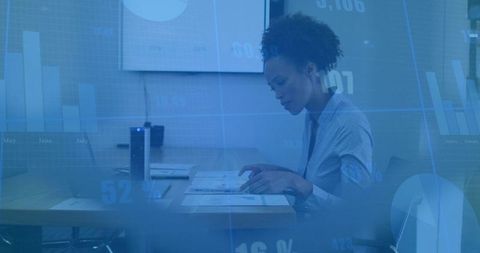 Businesswoman analyzing data, pointing at charts on conference table with analytics overlay