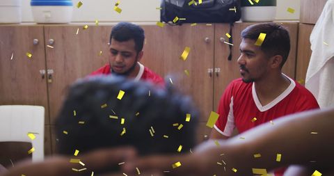 Football players celebrating victory in locker room with confetti
