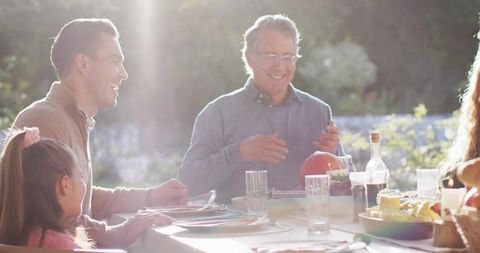 Multigenerational Family Carving Pumpkin and Sharing Meal at Sunlit Outdoor Dining Table