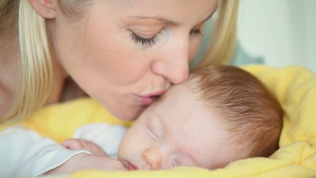 Tender close-up of mother kissing her sleeping baby, emphasizing love and bonding. Ideal for parenting blogs, childcare ads, family magazines, and social media posts celebrating motherhood.