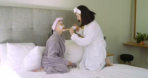Mother and Daughter Bonding Over Skincare Ritual in Bedroom
