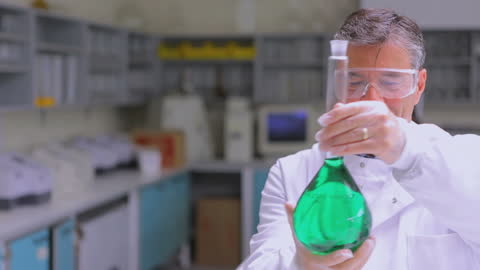 Scientist Holding Green Liquid in Laboratory with Research Team