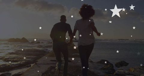 Couple Holding Hands on Pier with Ocean Sunset and Stars