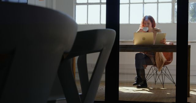 Remote worker reviewing documents while drinking coffee in modern home office - Download Free Stock Images Pikwizard.com