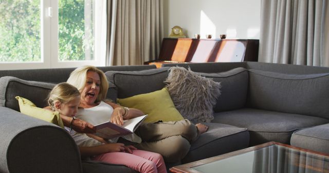 Grandmother Reading Book to Granddaughter on Sofa in Cozy Living Room - Download Free Stock Images Pikwizard.com