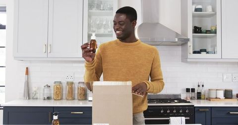Man Unpacking Amber Bottle in Modern Kitchen Interior