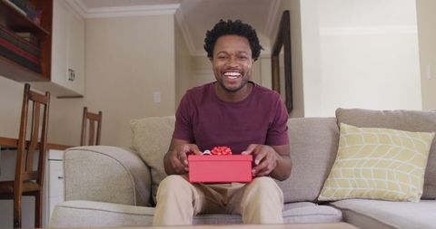 Joyful man on sofa holding gift box
