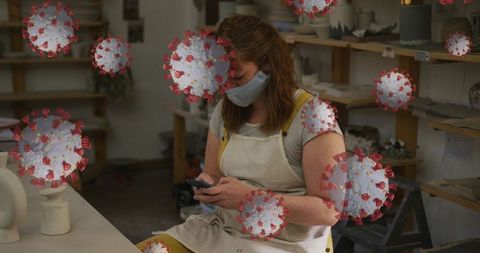 Woman in Pottery Studio Surrounded by COVID-19 Graphics