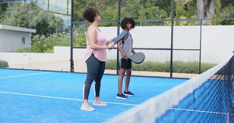 African american women practicing pickleball on blue court during coaching and training