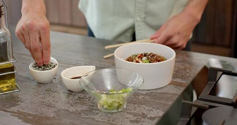 Chef sprinkling sesame seeds on gourmet rice bowl