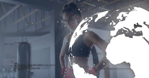 Woman Boxer Standing Confident in Industrial Gym Wearing Red Wraps with Globe Data Overlay
