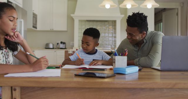 African american father, daugher and son sitting at kitchen table doing homework. staying at home in isolation during quarantine lockdown.