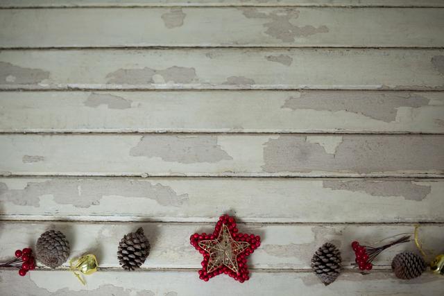 Rustic Christmas star and pine cones arranged on weathered wood background. Ideal for holiday greeting cards, festive invitations, seasonal blog posts, or DIY craft inspiration. Perfect for adding a vintage, natural touch to Christmas-themed projects.