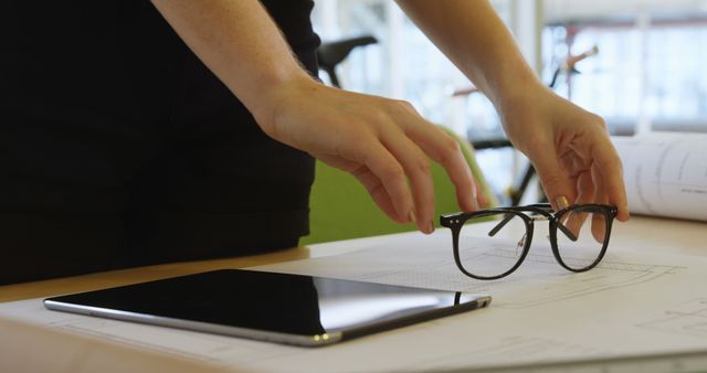 Designer Adjusting Eye Glasses on Workspace with Tablet and Blueprint - Download Free Stock Images Pikwizard.com