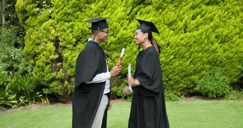 Smiling graduate couple sharing a moment outdoors