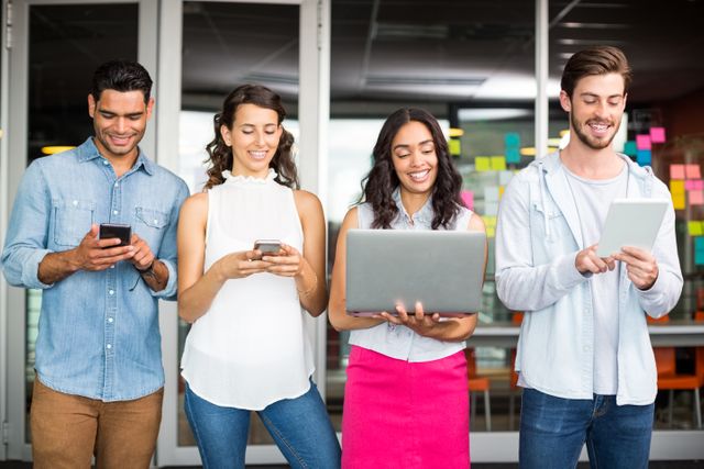 Smiling Young Professionals Using Digital Devices in Modern Office - Download Free Stock Images Pikwizard.com