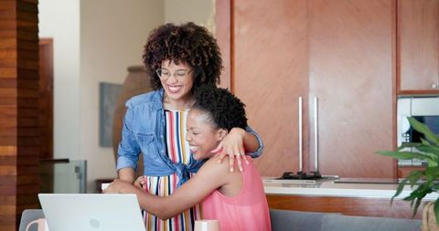Happy African American Couple Embracing at Home Near Laptop