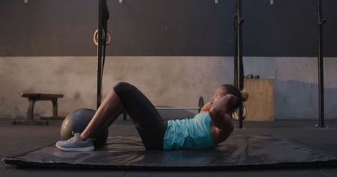 Athletic woman performing sit-ups with medicine ball in gym