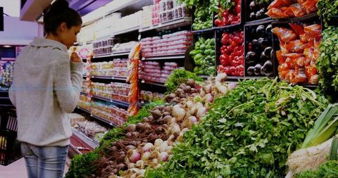 Woman Exploring Fresh Produce Section in Supermarket Aisle