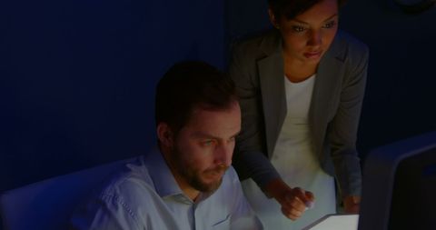 Young Professionals Discussing Critical Project in Dimly Lit Office