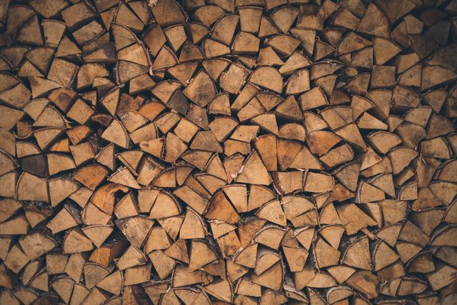 Pattern of stacked firewood logs displaying an appealing geometric and natural texture. Suitable for showcasing rustic themes, background designs, environmental campaigns, and concepts related to sustainability and fuel.
