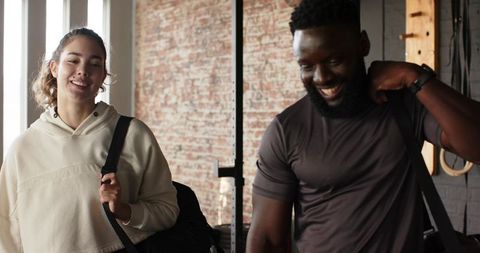 Diverse friends with duffel bags exiting contemporary workout studio