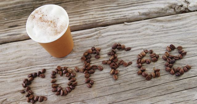 Coffee beans are arranged on a wooden surface to spell LOVE, next to a cup of cappuccino with foam, with copy space. It's a creative display that combines the passion for coffee with a message of affection.