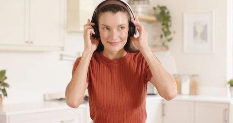 Young Woman Adjusting Headphones in Stylish Minimalist Kitchen